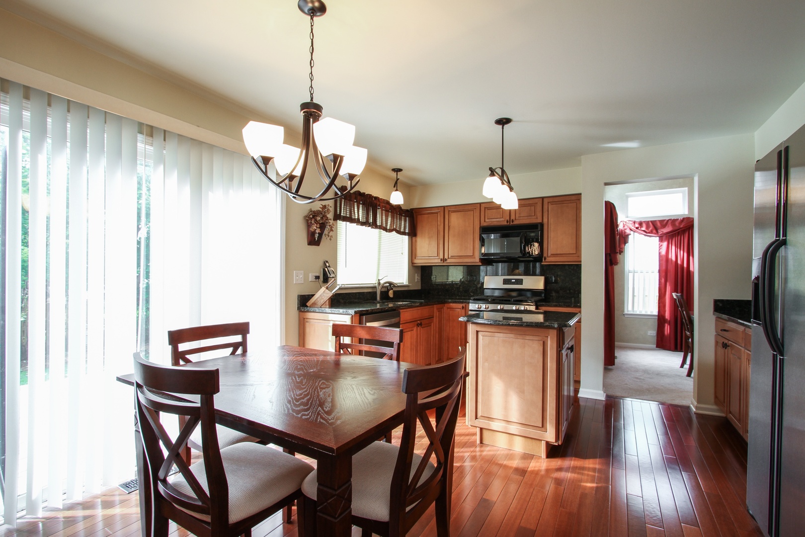 221 Ellis Road Lake In The Hills, IL 60156 - Photo 5 of 28 a kitchen with stainless steel appliances granite countertop a stove top oven a refrigerator a sink a dining table and chairs with wooden floor