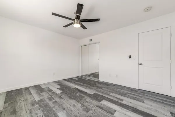 an empty room with a ceiling fan and wooden floor