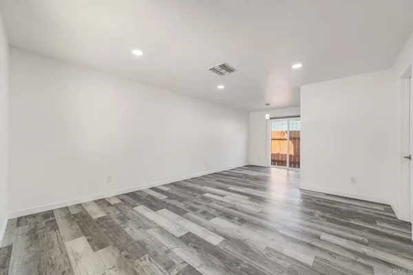 a view of empty room with wooden floor and windows