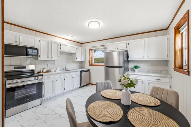 a kitchen with stainless steel appliances granite countertop a sink a stove a dining table and chairs