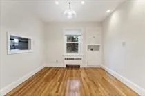a view of a room with wooden floor white walls and windows