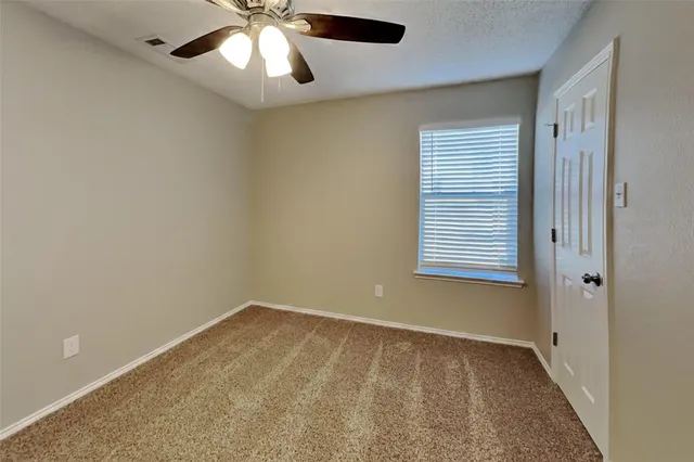 an empty room with a window and a fan