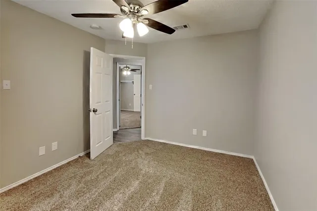 an empty room with a chandelier fan and closet area