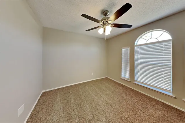 an empty room with windows and fan
