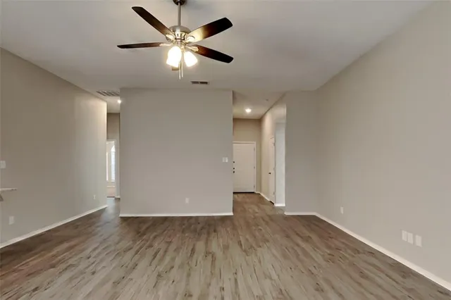 an empty room with wooden floor and a ceiling fan