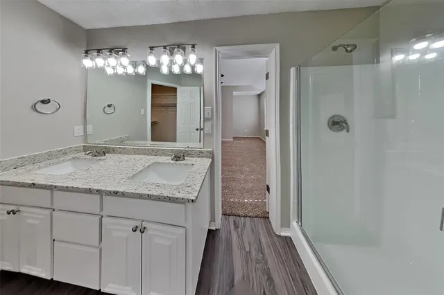 a bathroom with a granite countertop sink a large mirror and a shower