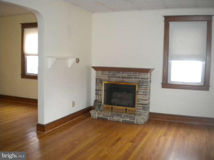 5527 Ashbourne Road Halethorpe, MD 21227 - Photo 9 of 30 an empty room with wooden floor and fireplace