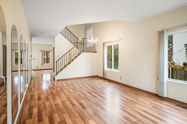 a view of empty room with wooden floor and fan