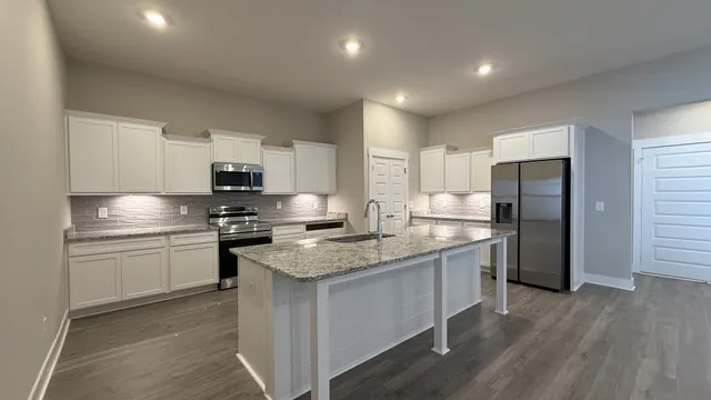 a kitchen with stainless steel appliances granite countertop a sink stove refrigerator and microwave
