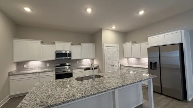 a kitchen with stainless steel appliances granite countertop a sink refrigerator and microwave