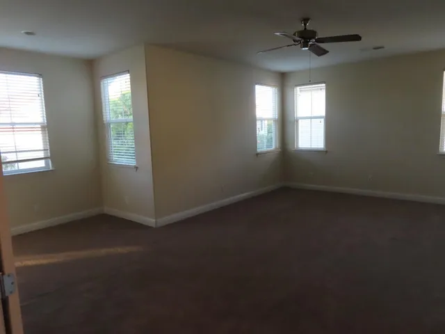 an empty room with windows and fan