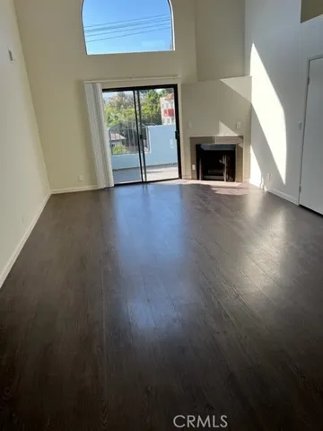 an empty room with wooden floor fire place and windows