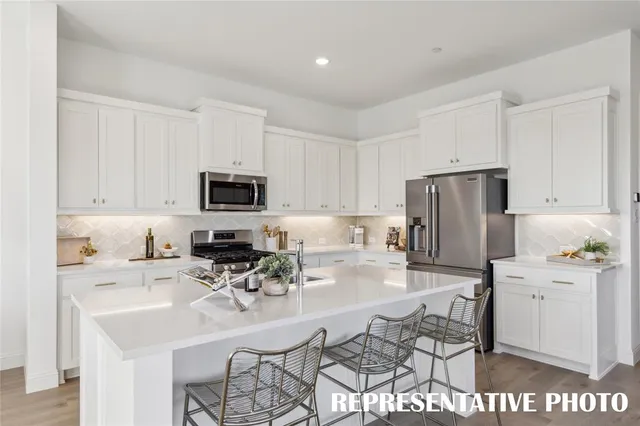 a kitchen with stainless steel appliances a dining table chairs refrigerator and sink