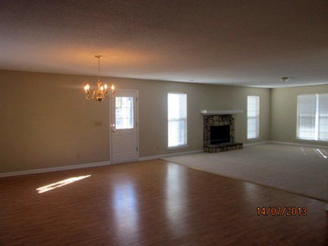 437 Comer Road Gray, GA 31032 - Photo 2 of 20 an empty room with wooden floor fireplace and window