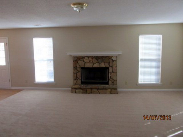 437 Comer Road Gray, GA 31032 - Photo 11 of 20 an empty room with a fireplace and windows