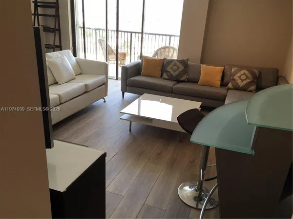 a living room with furniture wooden floor and a floor to ceiling window