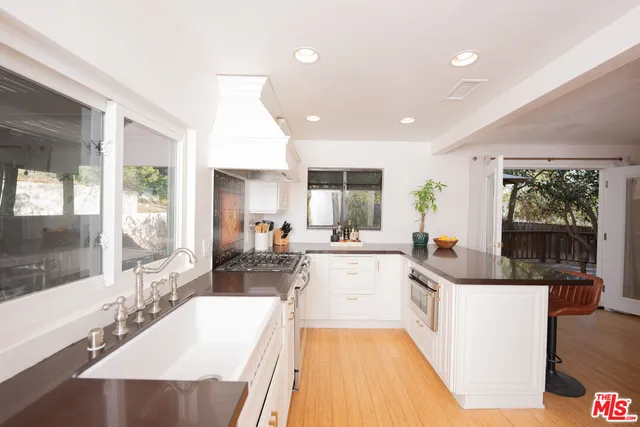 a large white kitchen with a large window and stainless steel appliances