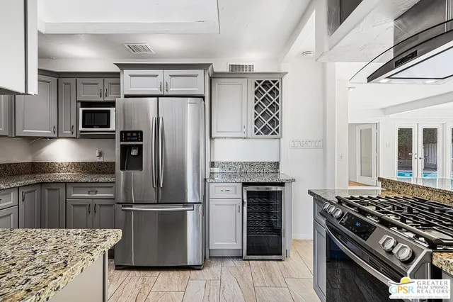 a kitchen with granite countertop a refrigerator and a stove top oven