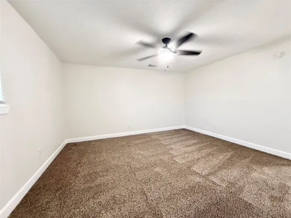 an empty room with a window and ceiling fan