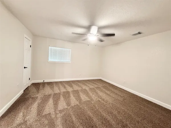 an empty room with a ceiling fan and a window