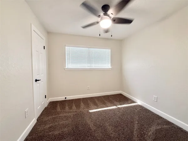 an empty room with a chandelier fan and windows