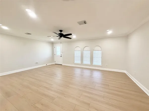 an empty room with wooden floor and windows