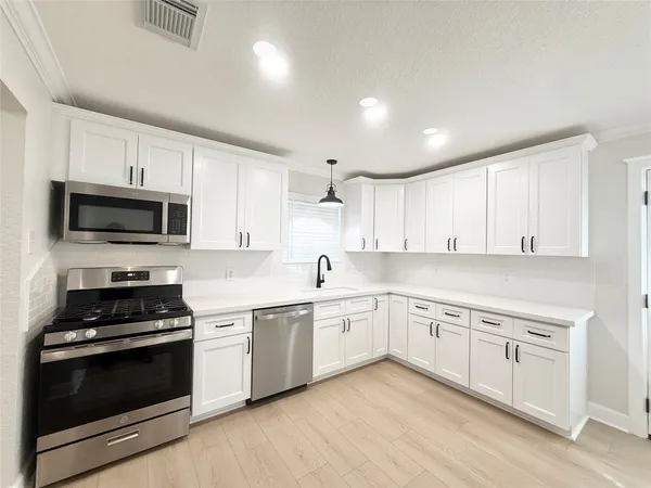 a kitchen with granite countertop white cabinets and stainless steel appliances
