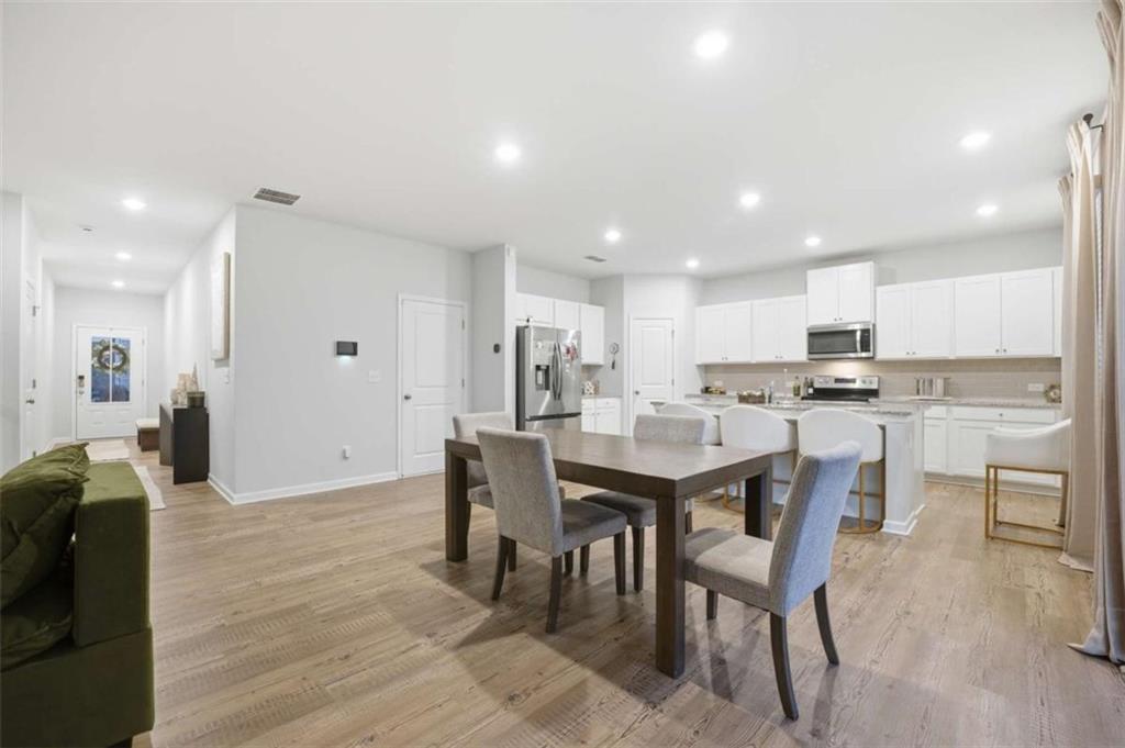 7129 Timberland Trail Lithonia, GA 30058 - Photo 13 of 43 a kitchen with a dining table chairs wooden floor appliances and cabinets