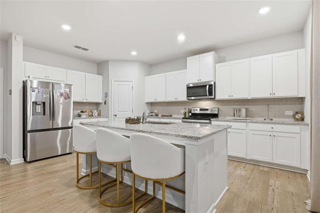 7129 Timberland Trail Lithonia, GA 30058 - Photo 14 of 43 a kitchen with stainless steel appliances granite countertop a stove a sink a refrigerator a microwave and white cabinets