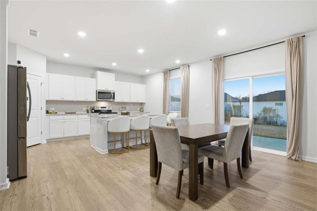 7129 Timberland Trail Lithonia, GA 30058 - Photo 26 of 43 a kitchen with a dining table chairs refrigerator and white cabinets
