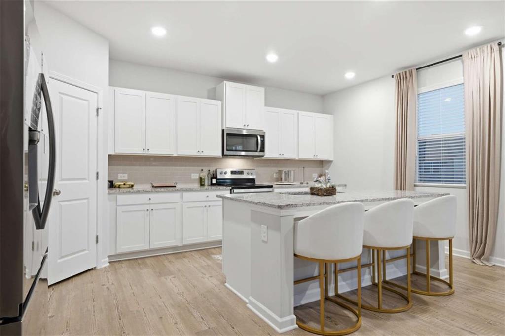 7129 Timberland Trail Lithonia, GA 30058 - Photo 28 of 43 a kitchen with stainless steel appliances granite countertop a stove a sink a refrigerator and white cabinets with wooden floor