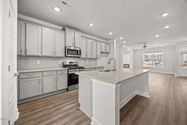 a kitchen with stainless steel appliances granite countertop a stove and a wooden floors