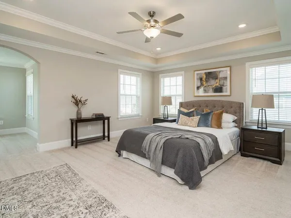 a spacious bedroom with a bed couch and windows