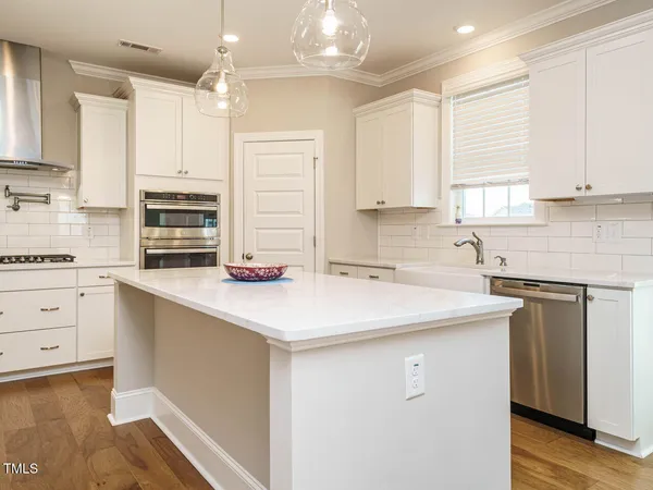 a kitchen with stainless steel appliances granite countertop a stove top oven a sink dishwasher and a dining table with wooden floor