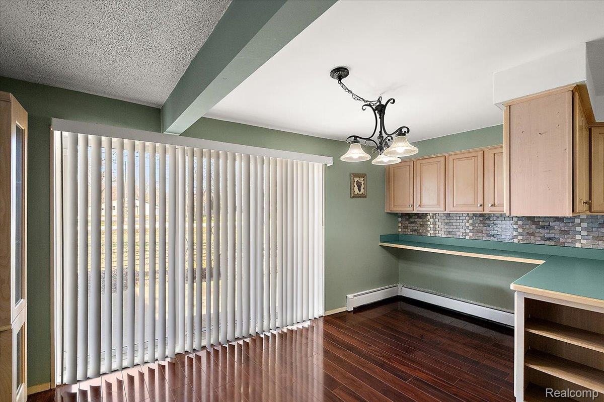 4705 Ketchum Road St. Clair, MI 48079 - Photo 18 of 58 Unfurnished dining area featuring dark wood-style floors, beam ceiling, suspended lighting, baseboard heating, and a textured ceiling