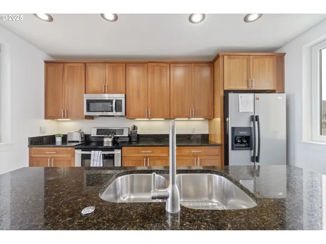 a kitchen with stainless steel appliances granite countertop a sink refrigerator and microwave