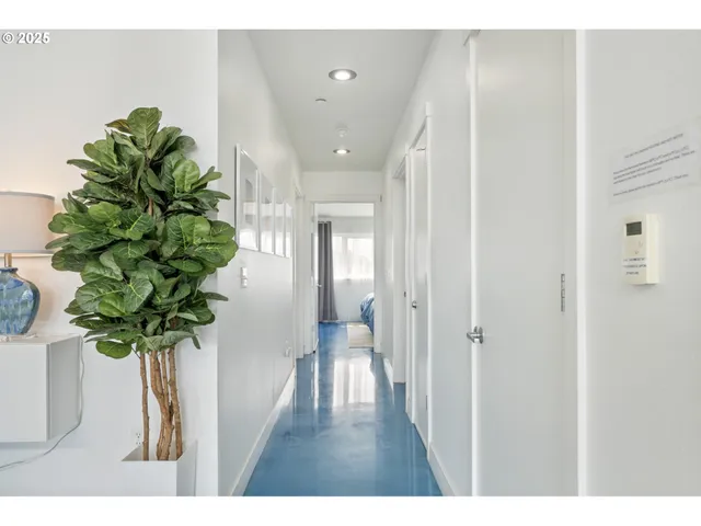 a hallway with painting on the wall and a potted plant