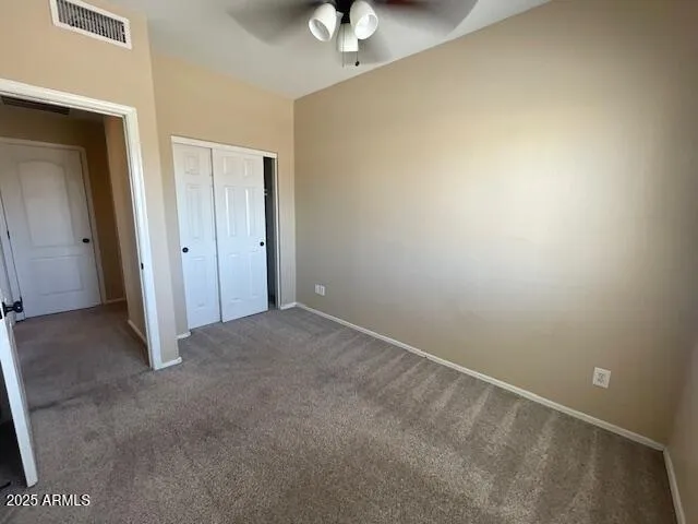 an empty room with a chandelier fan and windows