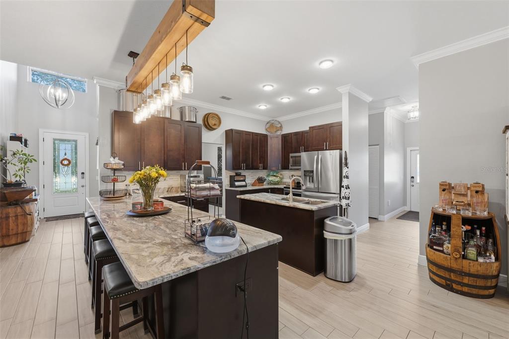 14582 Boland Avenue Spring Hill, FL 34610 - Photo 18 of 74 a kitchen with granite countertop kitchen island stainless steel appliances sink stove dining table and chairs