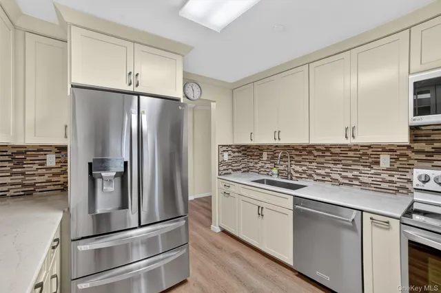 a kitchen with white cabinets stainless steel appliances and a window
