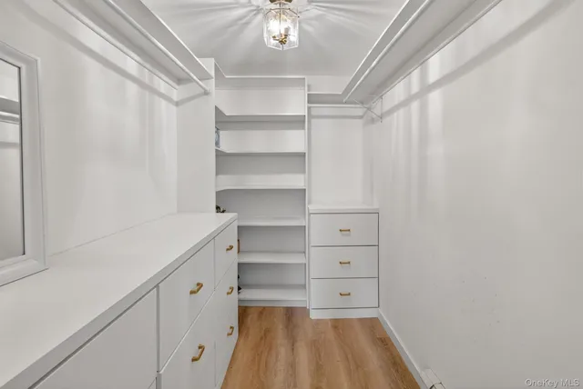 a view of an empty room with wooden floor and next to a window