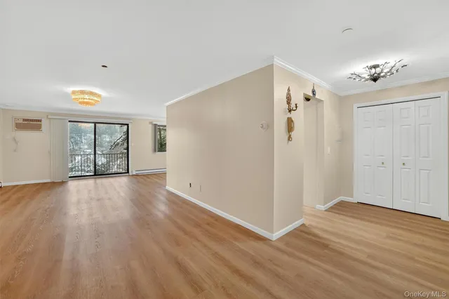 an empty room with wooden floor chandelier fan and windows