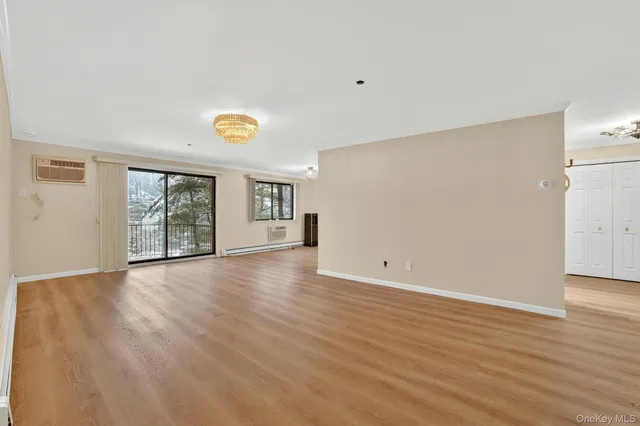 a view of an empty room with wooden floor and window