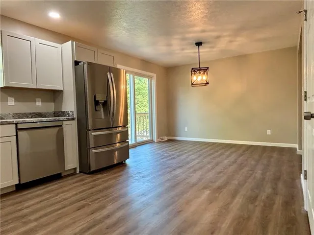 a kitchen with granite countertop a refrigerator and wooden floor