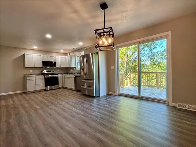 a view of a kitchen with stainless steel appliances granite countertop a refrigerator a oven with wooden floors