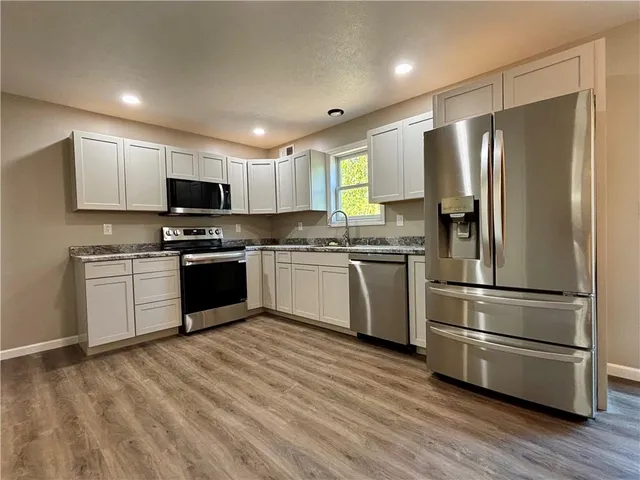 a kitchen with kitchen island granite countertop stainless steel appliances and sink