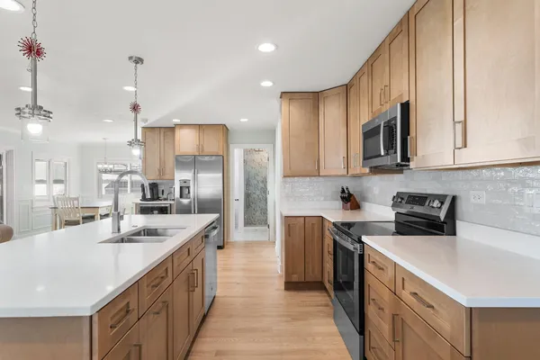 a kitchen with stainless steel appliances granite countertop a sink a stove and a refrigerator