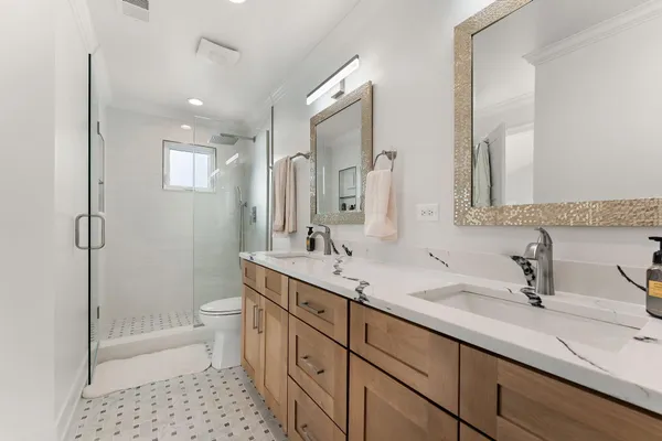 a bathroom with a double vanity sink toilet mirror and shower