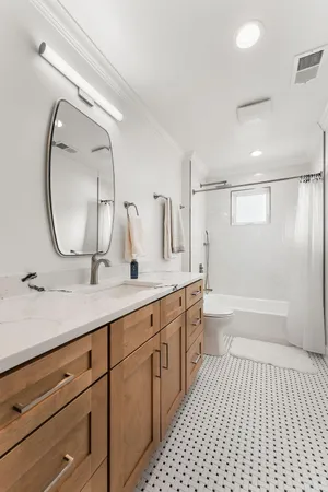 a spacious bathroom with a double vanity sink a mirror and a bathtub