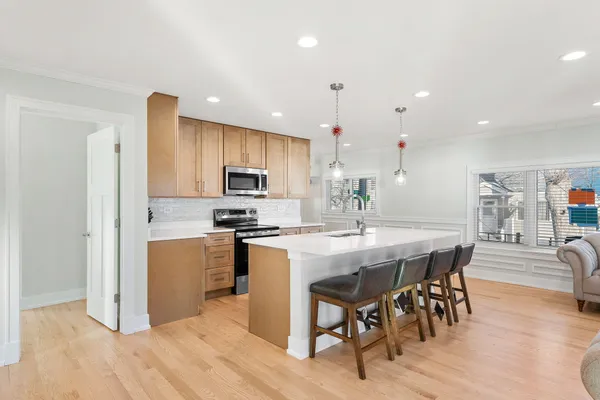 a kitchen with stainless steel appliances a dining table chairs stove refrigerator and cabinets